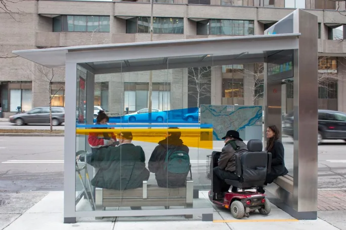 Riders wait at a covered bus stop for a Société de transport de Montréal bus.