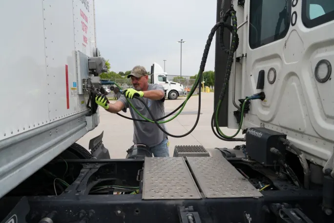 Truck driver checking the connections between tractor and trailer