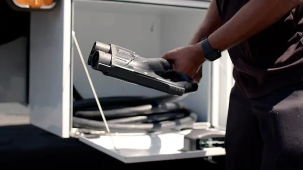 An Xos employee pulling charging cable out of a white container.