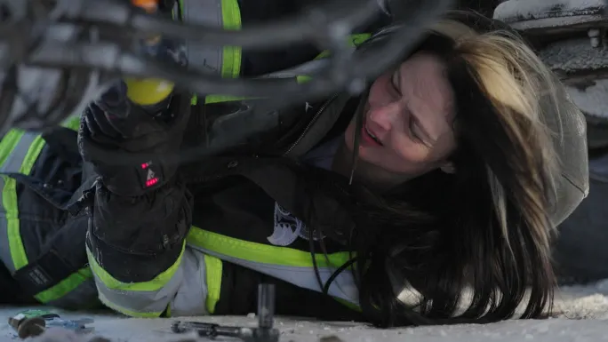 Ice Road Truckers' Lisa Kelly underneath a truck dealing with a problem on the road.