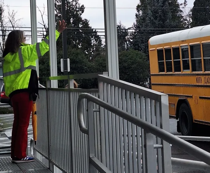 kathy calkins waves at a school bus 