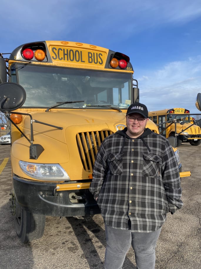 a man stands in front of a school bus outside