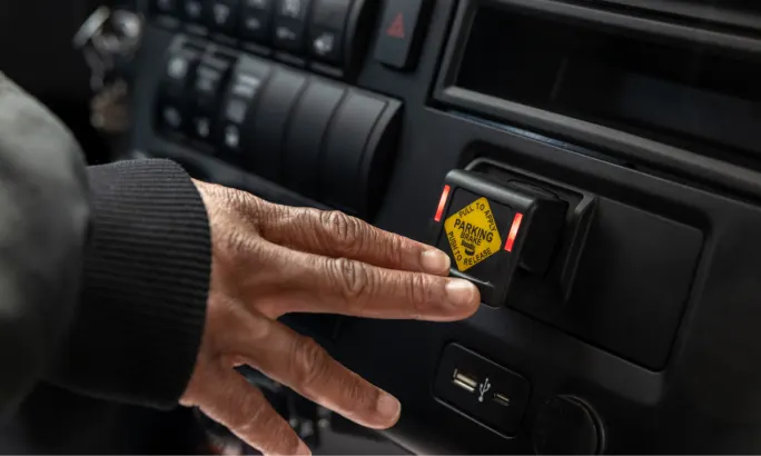 A hand pressing an emergency braking button.
