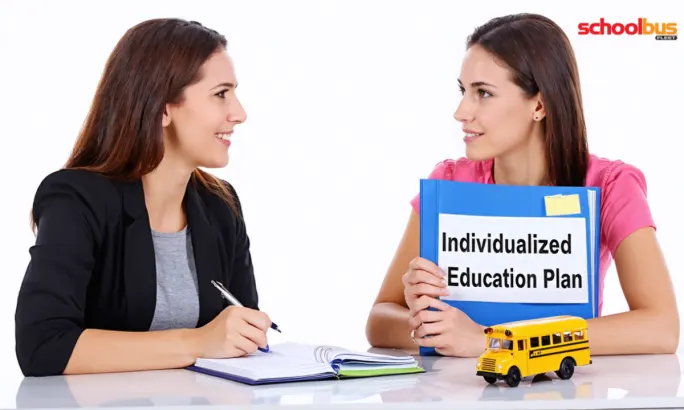 An image of two people engaged in conversation at a desk, with one holding a notebook labeled 
