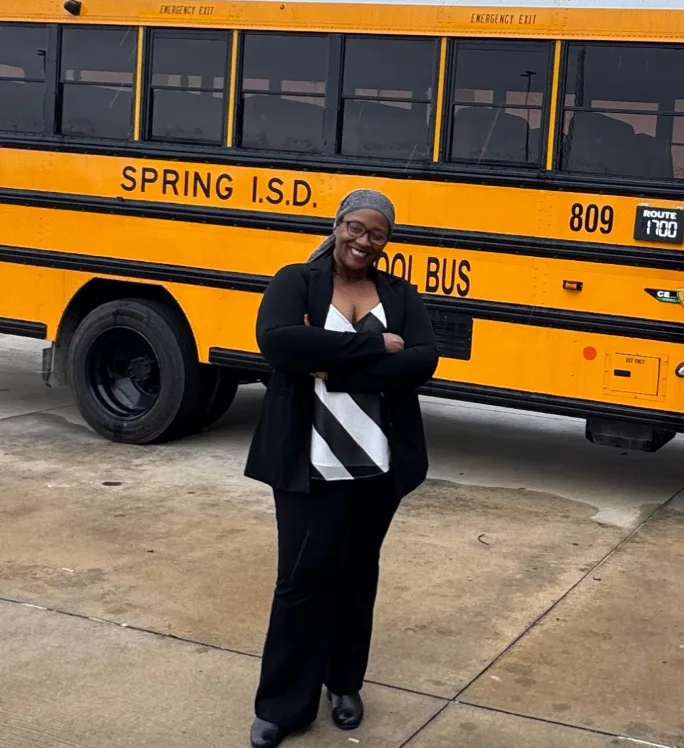 a woman stands in front of a school bus