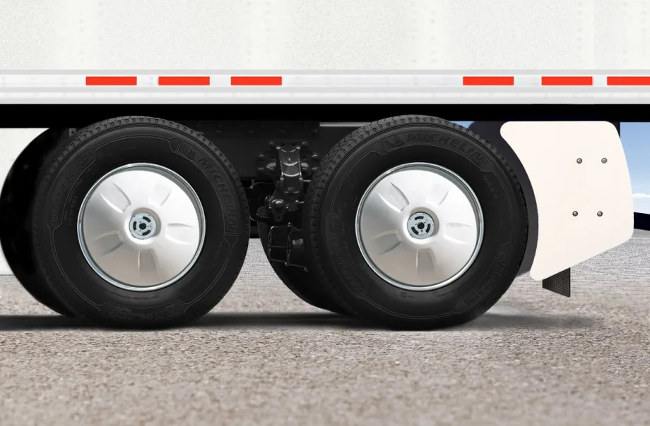 Close-up of trailer tandem wheels with silver FlowBelow wheel covers and a white AeroSlider fairing behind the rear tire.