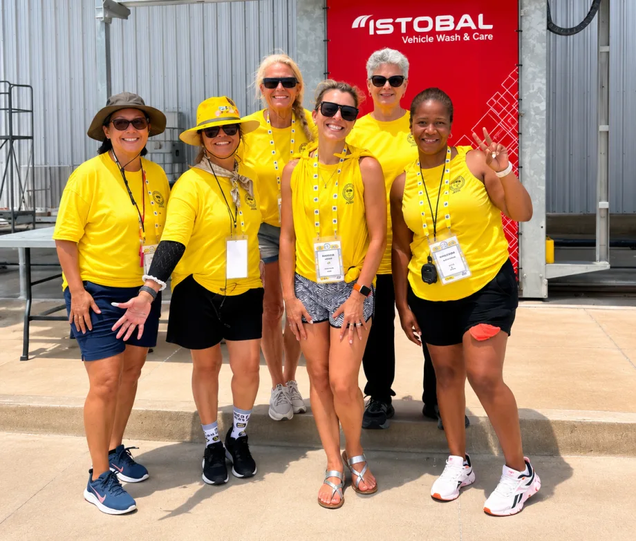 Six people stand next to each other in yellow shirts at the school bus driver competition