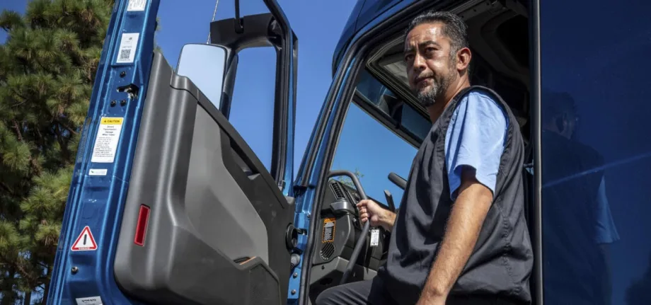A man standing at the driver entrance of a blue work truck.