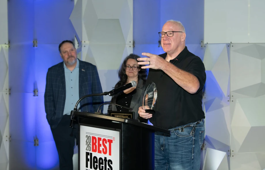 Photo of truck driver at podium holding award