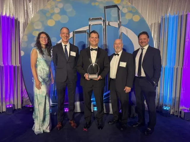 Tod Eskra stands on an award stage to accept recognition