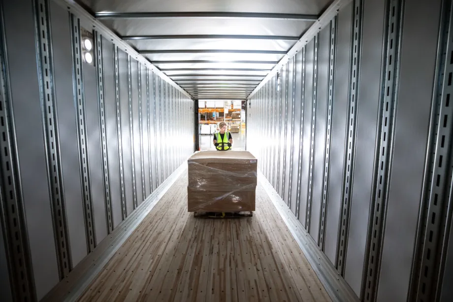 Empty trailer with worker loading a pallet of cargo