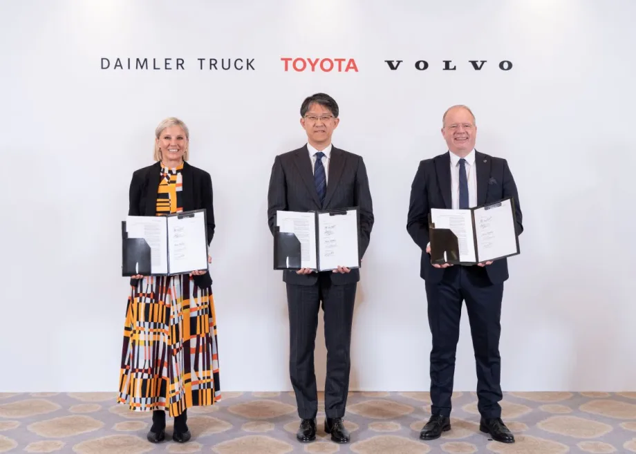 Three CEOs pose displaying binders with memorandum of understanding