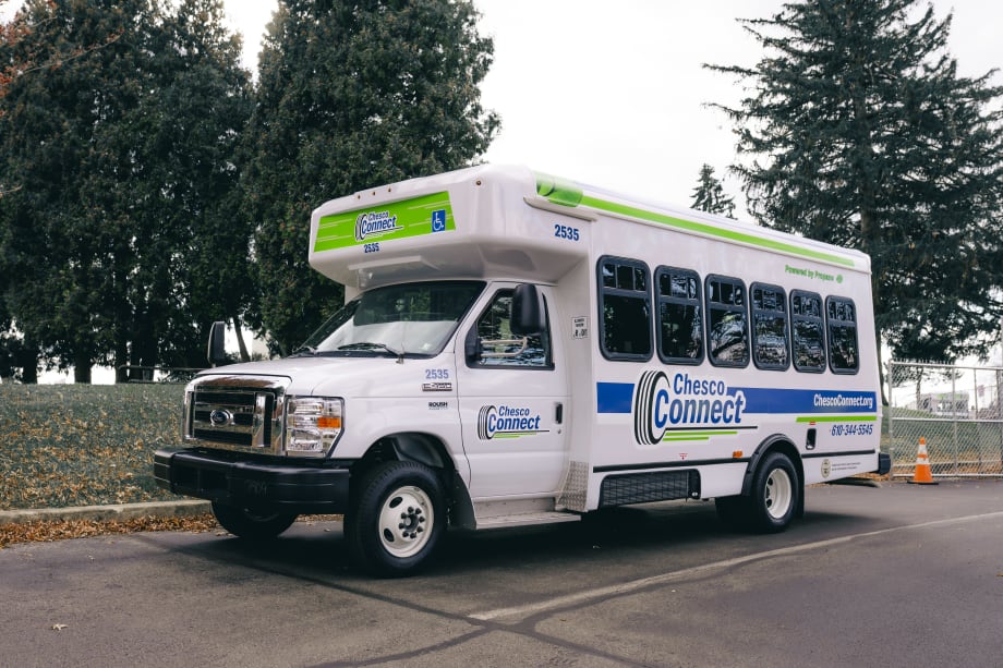 A white Chesco Connect paratransit bus parked outside.