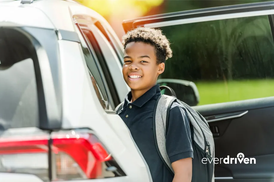 Student wearing a backpack stands beside an open passenger vehicle in an EverDriven alternative student transportation image.
