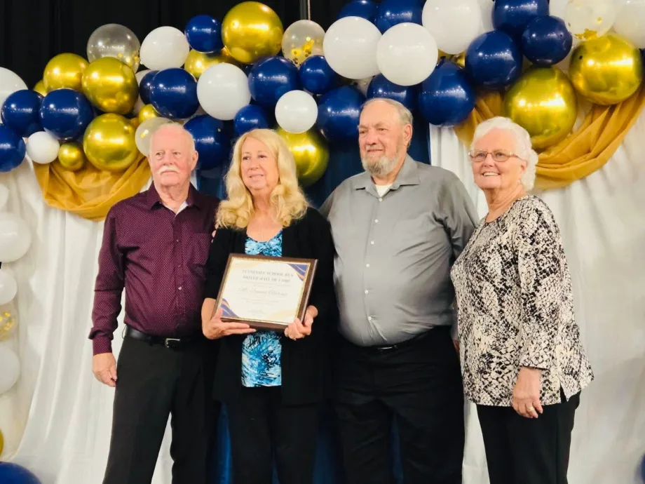 Frances Theiring stands with three other people holding an award