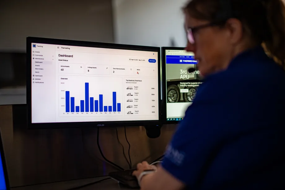 A monitor with a bar graph with a person sitting next to it wearing a headset.