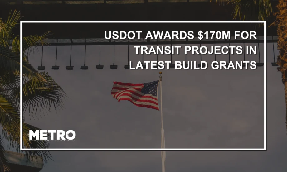 An image of an American flag waving under a bridge in Los Angeles with palm trees in the sunlight.