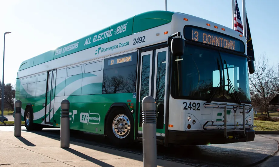A green and white Bloomington Transit electric bus parked in the street.