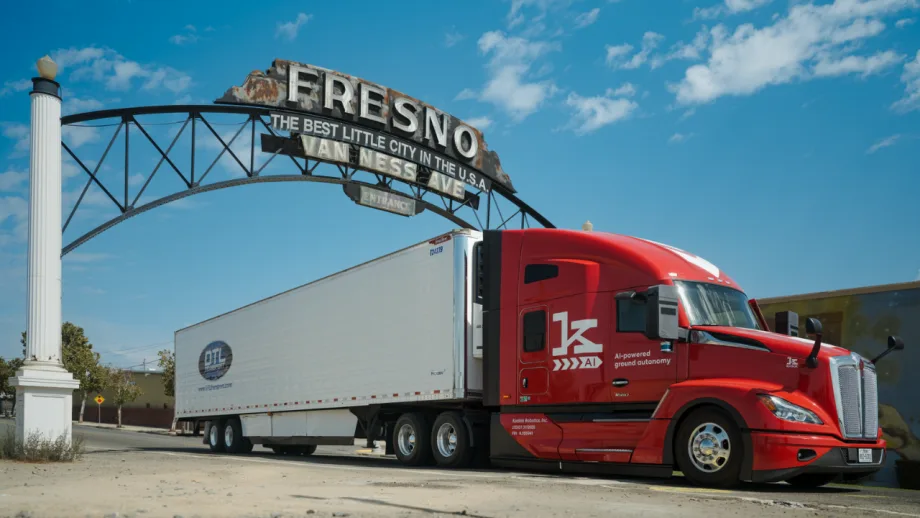 Red kodiak autonomous truck with trailer driving through Fresno arch
