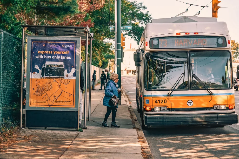 An MBTA bus with a passenger boarding at shelter.