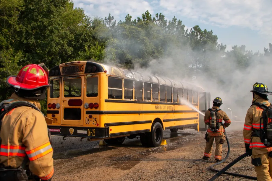 Firefighters spray water on a smoking Marietta City Schools school bus during a fire response drill.