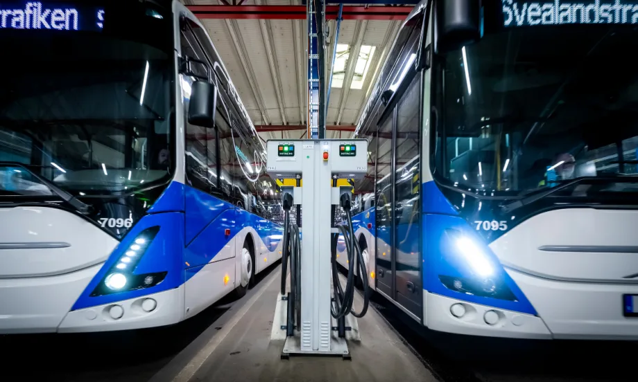 Two Swedish public transit buses next to a Hitachi Energy infrastructure.