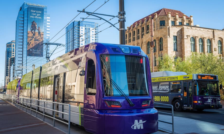 A Valley Metro light rail train and bus travel alongside each other in downtown Phoenix.