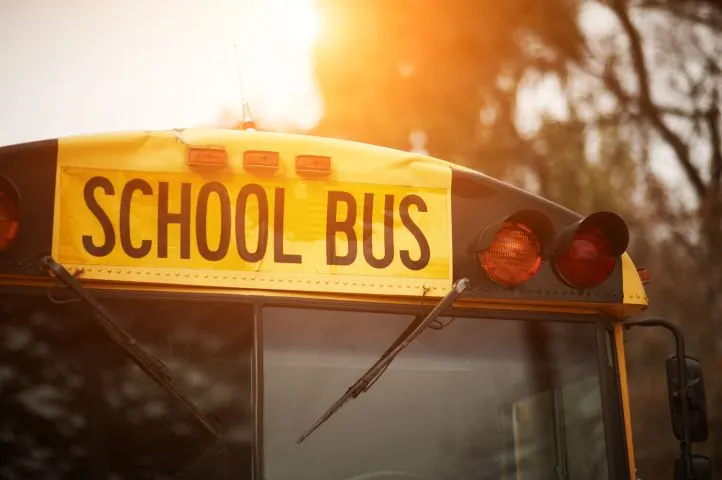 the top of a school bus is illuminated by a rising sun behind it