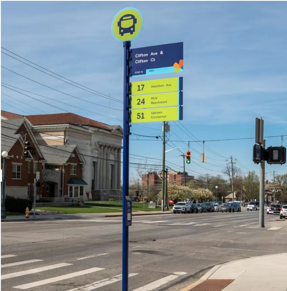 New Cincinnati Metro bus stop sign with large route numbers and clear layout at a city intersection, part of a systemwide signage upgrade initiative.