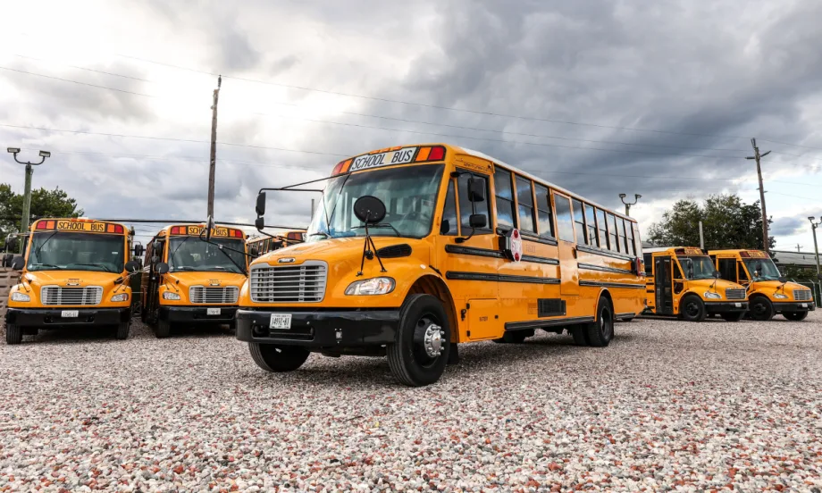A line up of school buses with one out front of the group.
