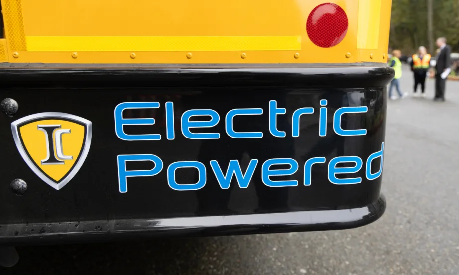 The back right corner of a school bus with blue text on the bumper reading "Electric Powered".