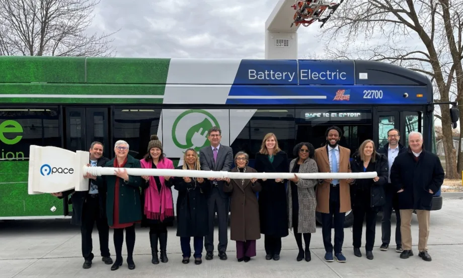 A group of people pose in front of a battery electric transit bus.