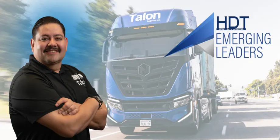 Hispanic man stands with arms crossed with electric Nikola truck in the background