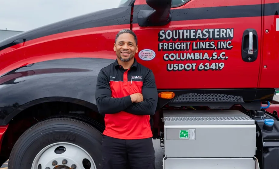 Photo of smiling truck driver Harold Perry with arms crossed in front of Southeastern Freight Lines truck
