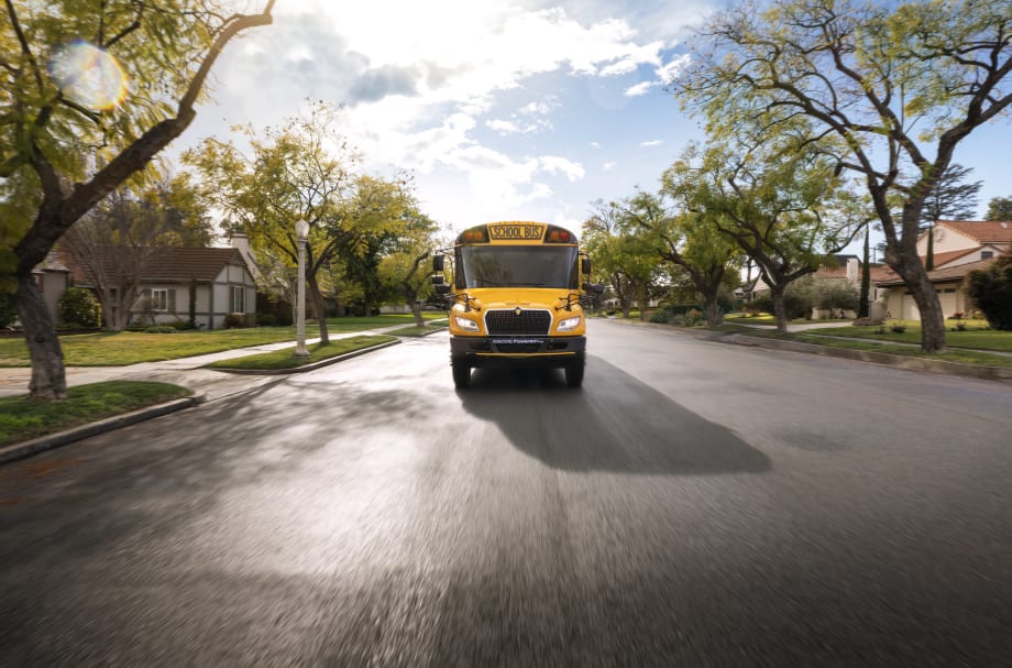 Front view of an IC Bus next generation electric CE Series bus driving on a suburban street.