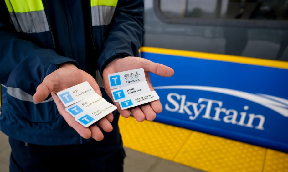 A TransLink SkyTrain worker holds up 6 language pins.