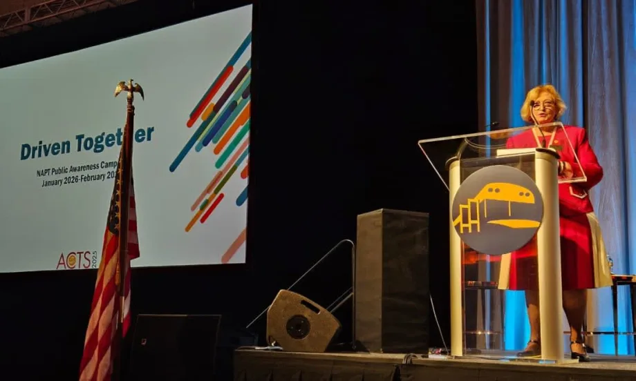 Molly McGee Hewitt stands at a podium on a stage with a screen behind her that says "Driven Together" and the NAPT logo