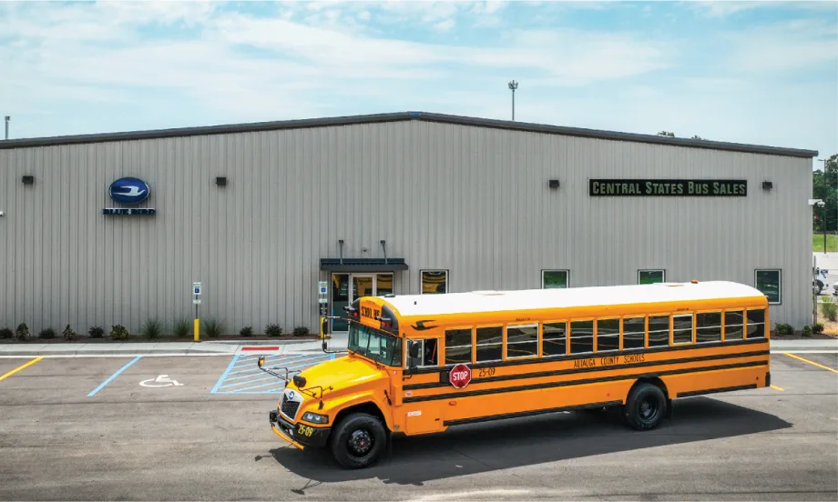 A school bus parked in front of a warehouse building.