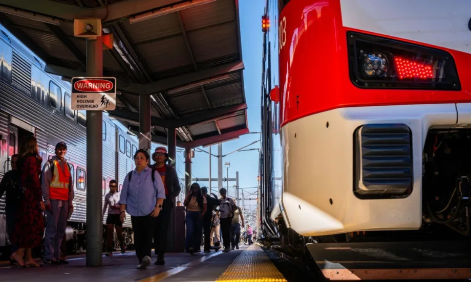 Low view of a Caltrain platform with a train parked at it with passengers nearby.