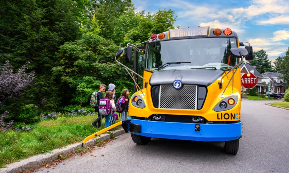 A Canadian LION school bus picks up students at a bus stop.