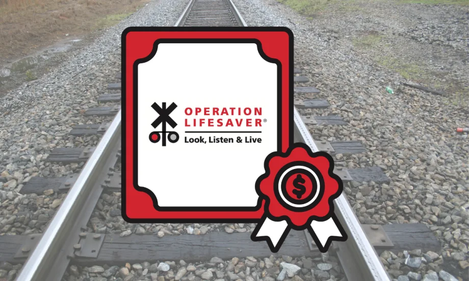 Operation Lifesaver rail safety grant graphic displayed over railroad tracks, highlighting federal funding for crossing safety and trespass prevention campaigns.